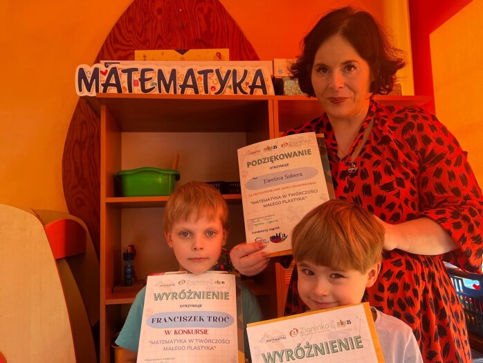 nauczycielka i dwoje dzieci pozują z dyplomami, w tle napis matematyka